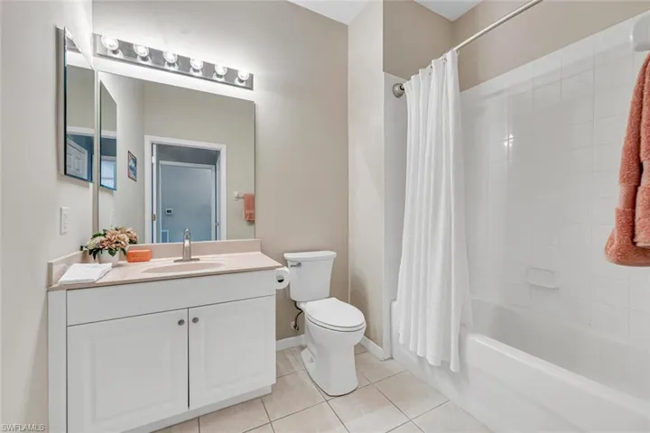 Full bath with toilet, vanity, tile patterned flooring, shower / bath combo with shower curtain, and baseboards