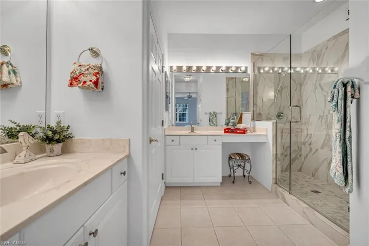 Full bathroom with two vanities, tile patterned flooring, a sink, and a marble finish shower