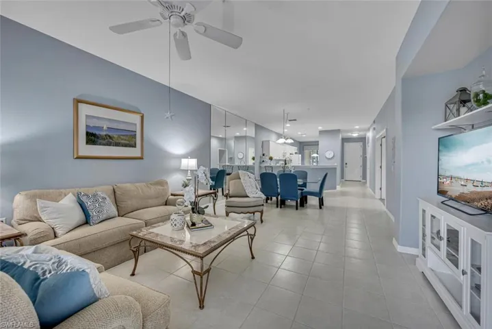 Tiled living room with a ceiling fan and baseboards