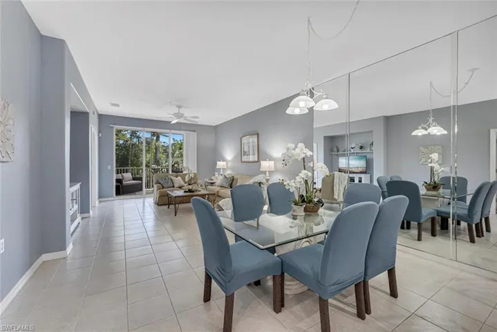 Dining room featuring ceiling fan with notable chandelier, baseboards, and light tile patterned floors