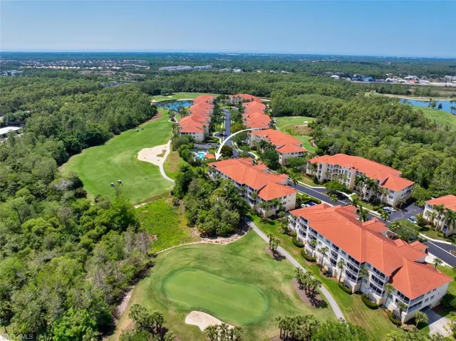 Birds eye view of property with view of golf course, a water view, and a view of trees
