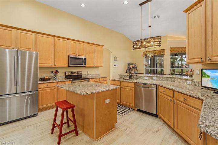 Large kitchen with granite tops, stainless steel appliances, wood cabinetry.