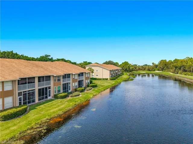 Waterfront property featuring multiple screened balconies and patios, mature landscaping, and an adjacent golf course