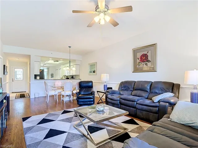 Wood-finish flooring, ceiling fan, white wall trim, recessed lighting, and kitchen pass-through