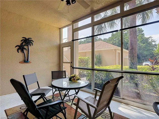 Screened patio featuring a ceiling fan, textured walls, and a glass-paneled door