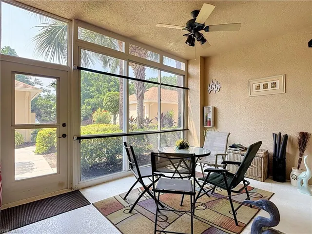 Screened-in patio with full-height windows, a ceiling fan with integrated lighting, and textured wall finishes