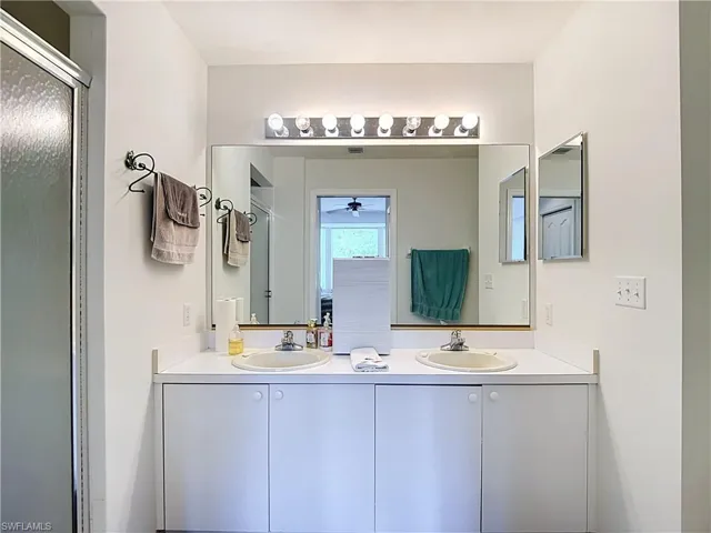 Double vanity with integrated sinks, white cabinetry, and a chrome light fixture