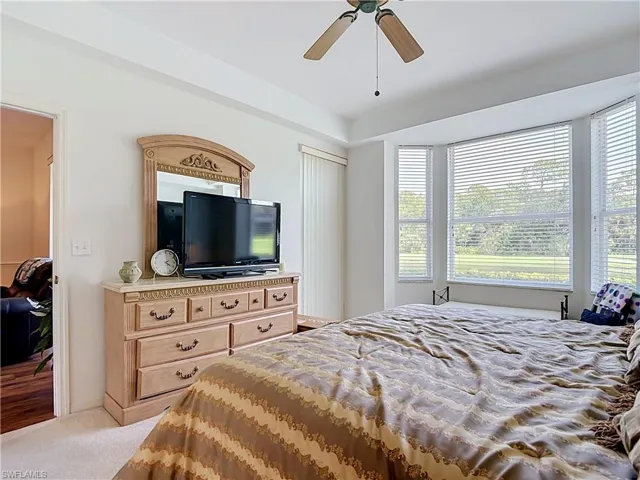 Bay window with multiple windows, ceiling fan, and carpeted flooring