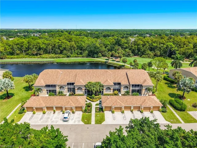 Two-story property featuring a golf course, expansive water feature, multiple garages, and mature landscaping
