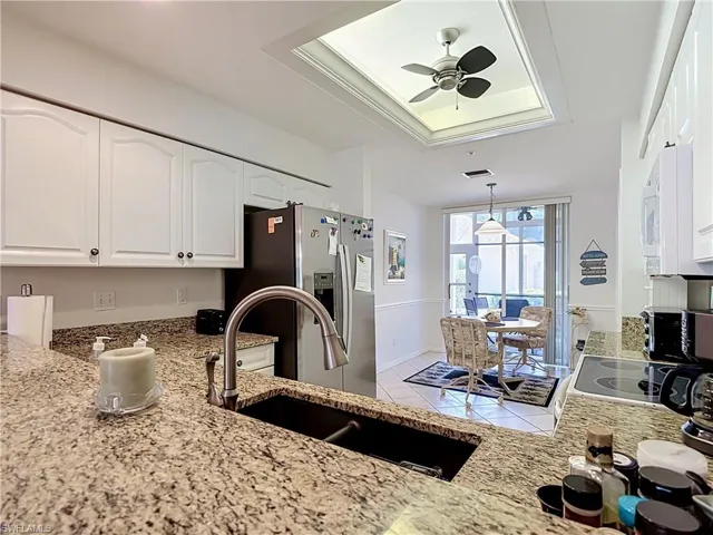 Kitchen featuring granite countertops, white cabinetry, a built-in stainless steel refrigerator, and a stainless steel sink with a gooseneck faucet