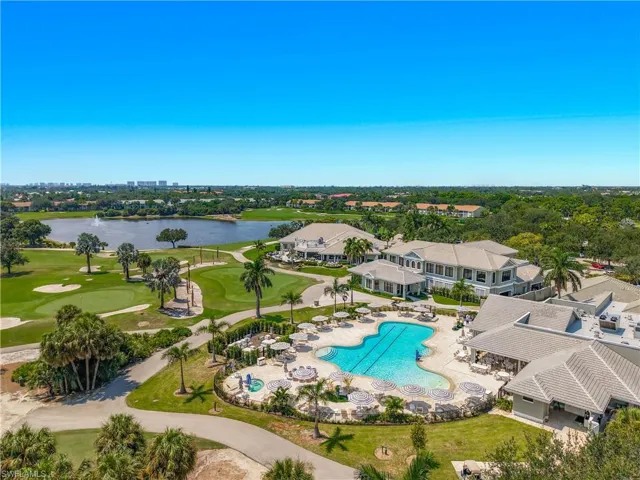 Lakeside golf course with manicured greens, expansive water feature, large swimming pool, and multiple buildings with tile roofs