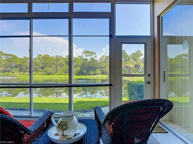 Expansive glass windows and a glass-paneled door frame a serene water feature and lush green landscape