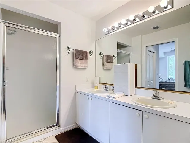 Dual vanity with integrated sinks, ample counter space, built-in cabinetry, and a full-width mirror with overhead lighting