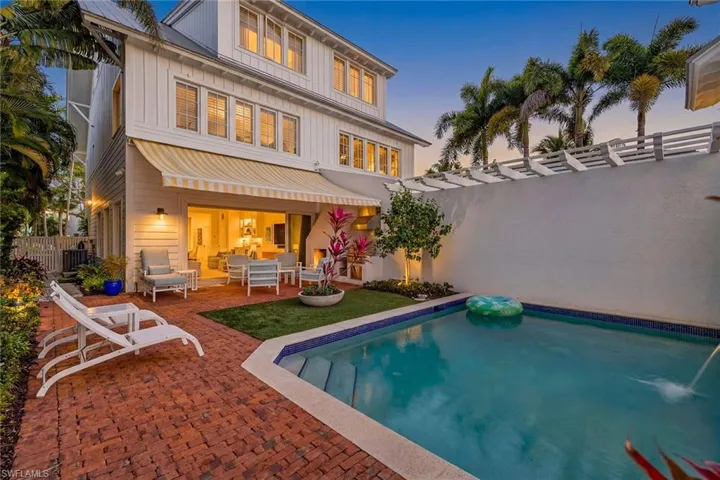 Back of property at dusk featuring a patio, an outdoor living space, a fenced backyard, board and batten siding, and a pergola