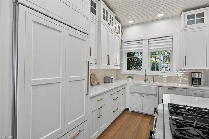 Kitchen featuring glass insert cabinets, light stone countertops, gas range oven, white cabinets, and recessed lighting