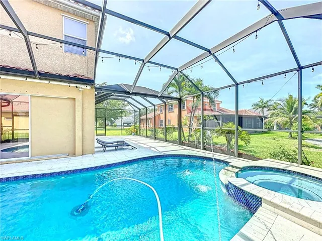 View of swimming pool with a patio area, a pool with connected hot tub, a lanai, and a yard