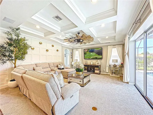 Living room featuring crown molding, carpet flooring, coffered ceiling, arched walkways, and beamed ceiling
