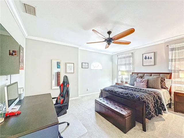 Bedroom featuring ornamental molding, carpet, ceiling fan, and a textured ceiling