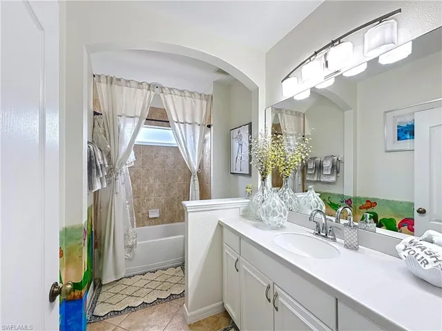 Bathroom with vanity, shower / bath combo, and tile patterned flooring