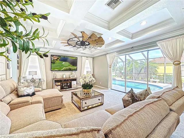 Carpeted living room with a sunroom, crown molding, coffered ceiling, ceiling fan, and beam ceiling