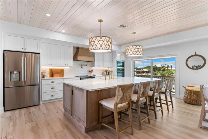 Gourmet kitchen featuring a large island with seating, stainless steel appliances, white cabinetry, and wood-finish flooring