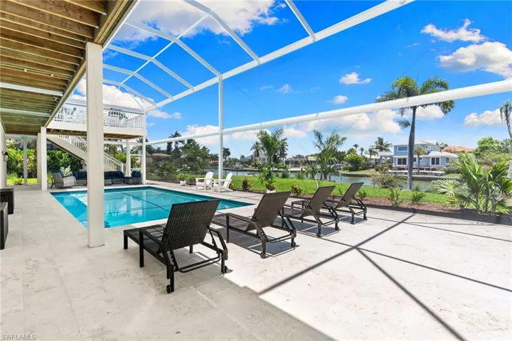 Screened outdoor living area with a rectangular pool, extensive paver patio, and water frontage