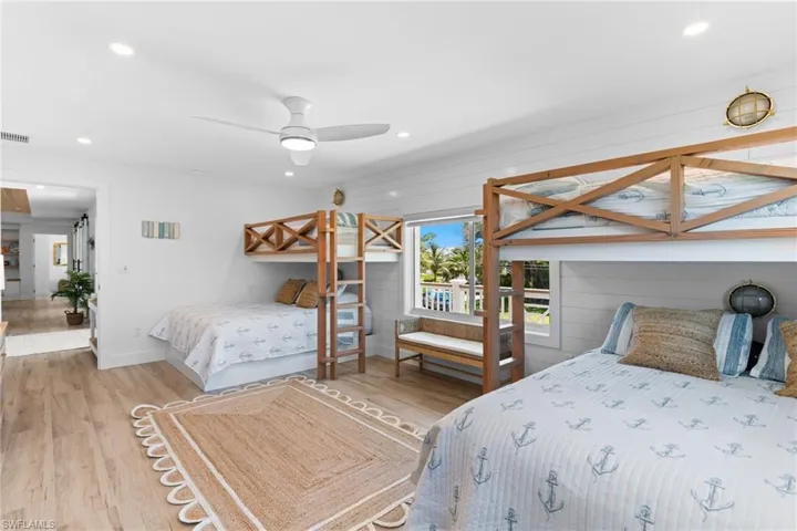 Bright room featuring two built-in bunk beds with natural wood frames, wood-finish flooring, white shiplap wall accents, and recessed lighting
