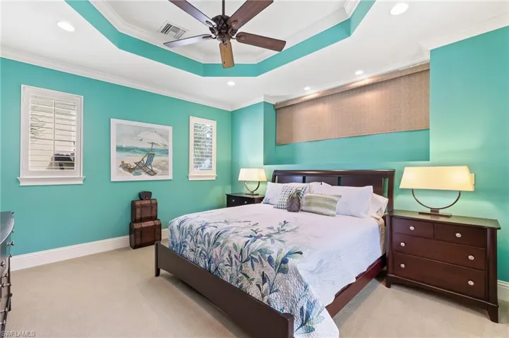 Bedroom featuring a tray ceiling, crown molding, carpet, recessed lighting, and a ceiling fan