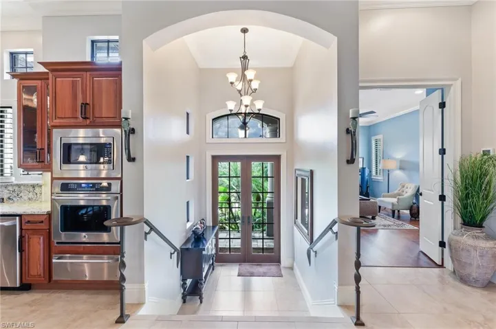 Entrance foyer featuring crown molding, plenty of natural light, french doors, light tile patterned floors, and a high ceiling