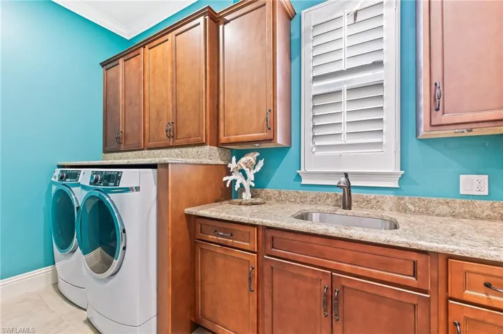Laundry area with washer and dryer, ornamental molding, and cabinet space