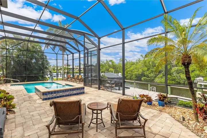 View of pool featuring a water view, a sunroom, a lanai, and a patio