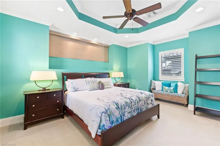 Carpeted bedroom with a raised ceiling, crown molding, recessed lighting, and ceiling fan