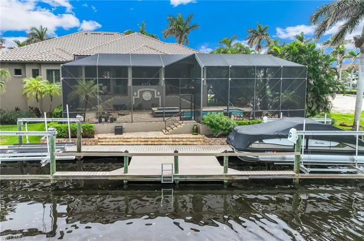 Dock with a pool, boat lift, a lanai, a sunroom, and a water view