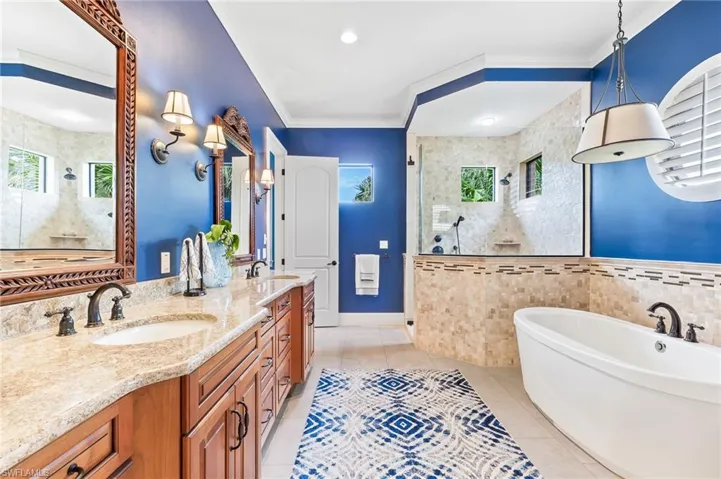 Full bathroom with a walk in shower, a soaking tub, ornamental molding, double vanity, and light tile patterned floors