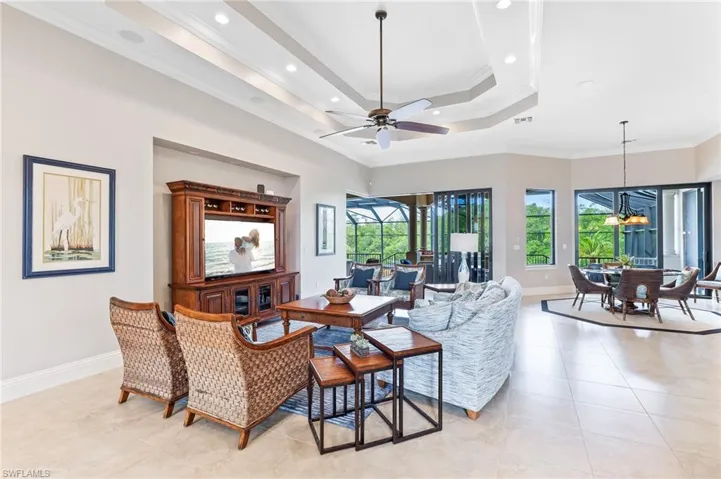 Living room with ornamental molding, a raised ceiling, plenty of natural light, light tile patterned flooring, and recessed lighting