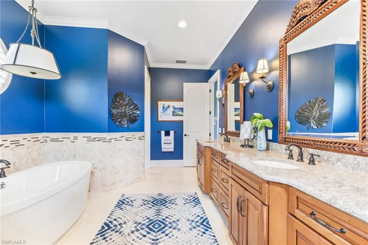 Bathroom featuring ornamental molding, a soaking tub, double vanity, light tile patterned floors, and recessed lighting