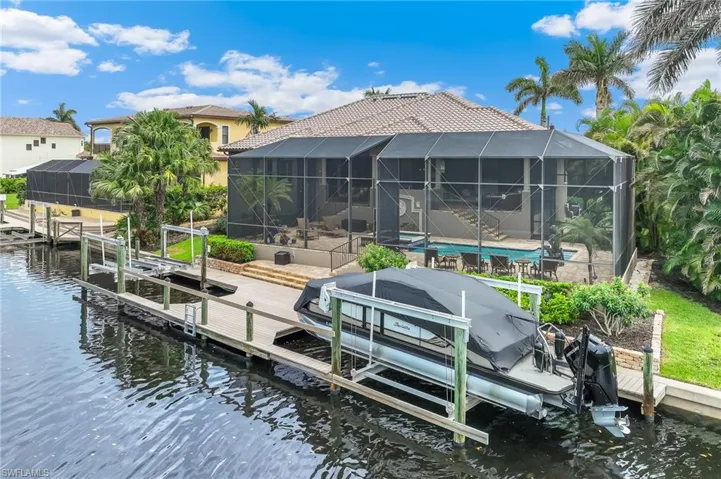 Dock area with boat lift, a water view, glass enclosure, and a sunroom