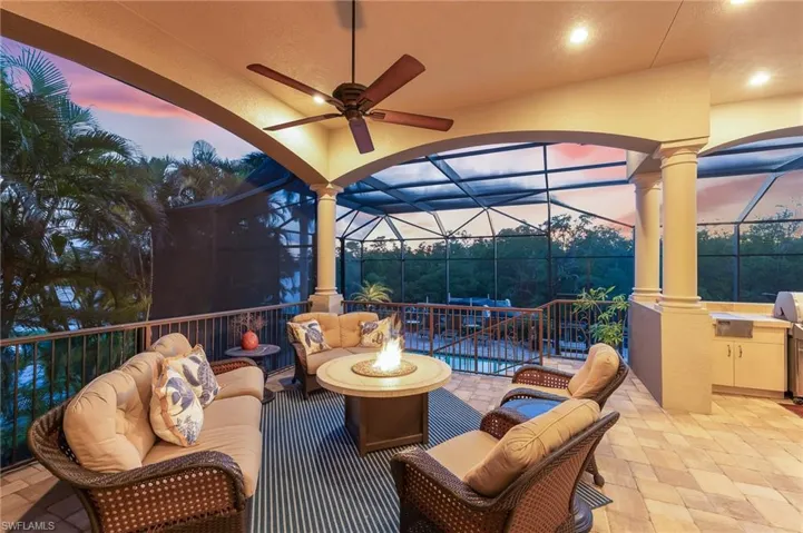 Patio terrace at dusk featuring an outdoor living space with a fire pit, an outdoor kitchen, a lanai, ceiling fan, and a sunroom