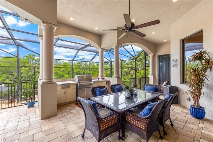 View of patio / terrace with an outdoor kitchen, outdoor dining area, a sunroom, and glass enclosure