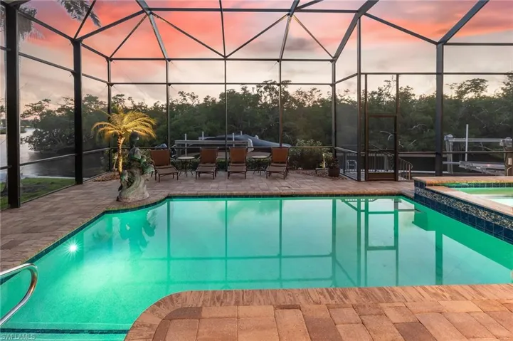 View of swimming pool featuring glass enclosure, a sunroom, and a patio