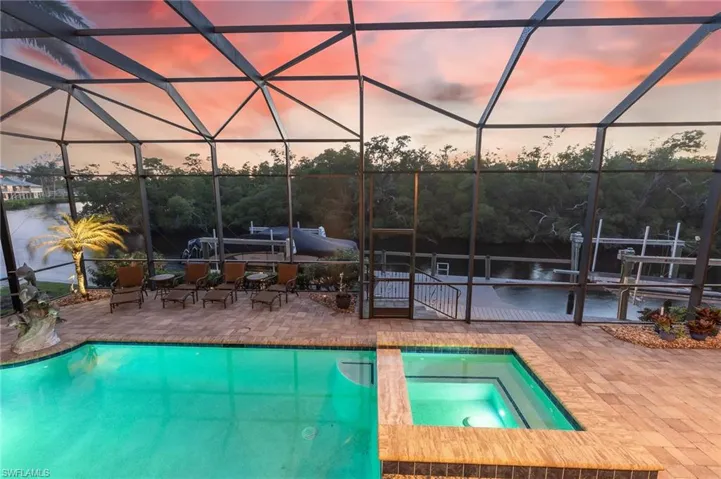 View of pool with a sunroom, glass enclosure, a pool with connected hot tub, and a patio