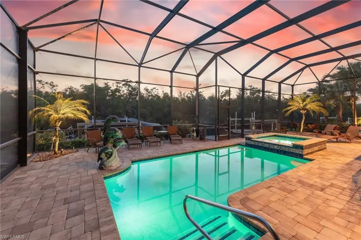 Pool at dusk with a sunroom, a patio area, and a lanai