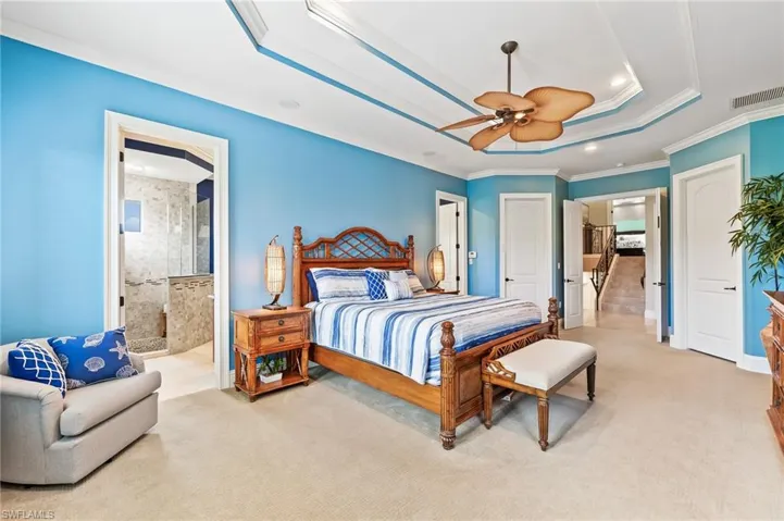 Bedroom featuring light colored carpet, ornamental molding, a tray ceiling, recessed lighting, and a ceiling fan