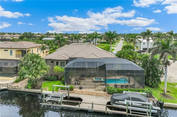 Dock area featuring boat lift, a sunroom, glass enclosure, an outdoor pool, and a water view