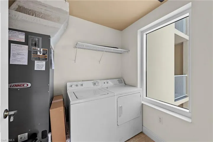 Laundry area featuring light tile floors and washing machine and clothes dryer
