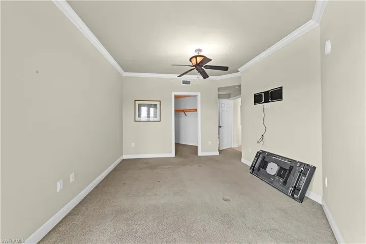 Carpeted spare room featuring ceiling fan and ornamental molding