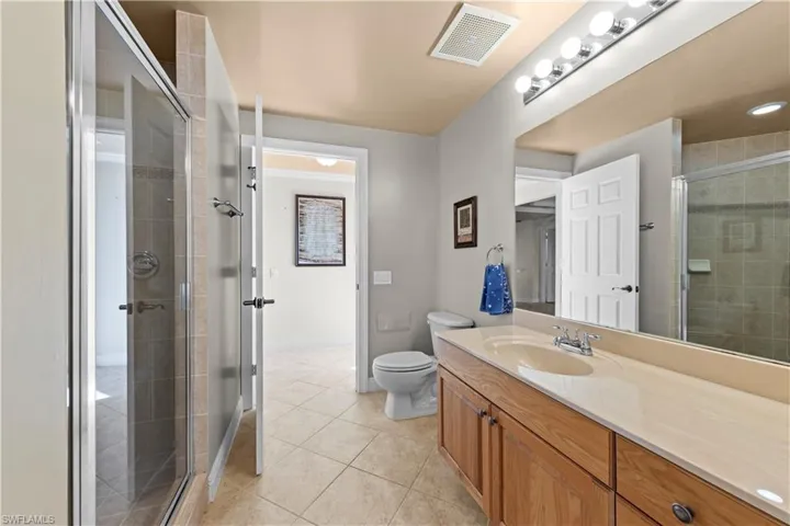 Bathroom with walk in shower, tile flooring, toilet, and vanity with extensive cabinet space