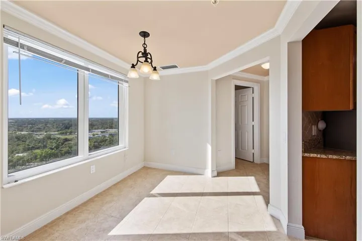 Tiled dining area with a chandelier and ornamental molding