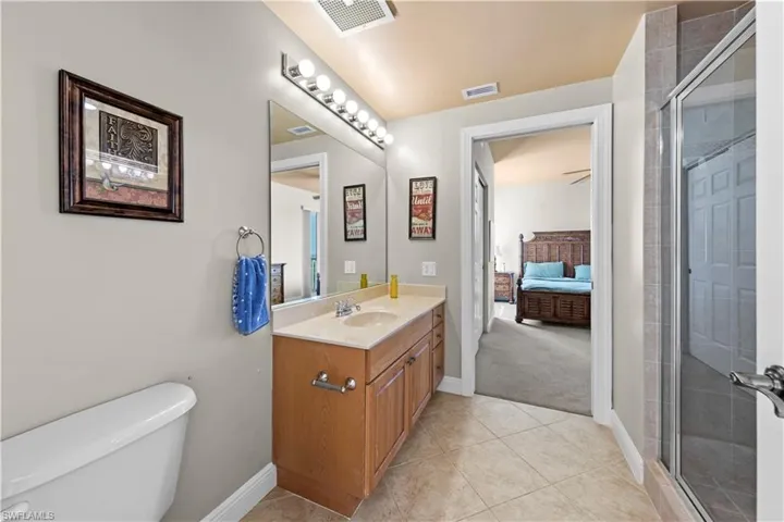 Bathroom with tile floors, an enclosed shower, large vanity, and toilet