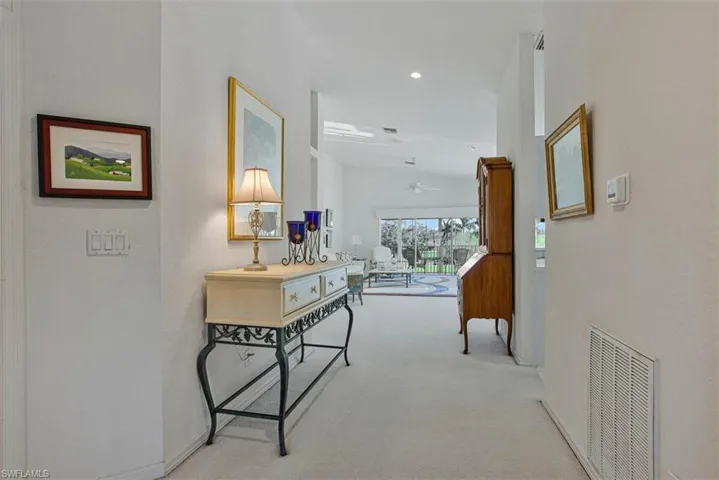 Hall with light colored carpet, lofted ceiling, and recessed lighting